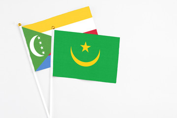 Mauritania and Comoros stick flags on white background. High quality fabric, miniature national flag. Peaceful global concept.White floor for copy space.