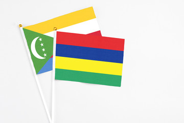 Mauritius and Comoros stick flags on white background. High quality fabric, miniature national flag. Peaceful global concept.White floor for copy space.