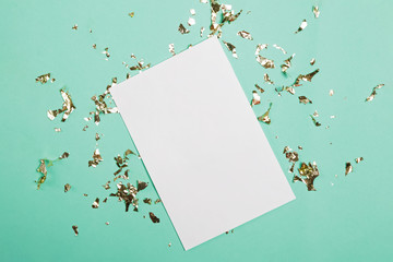 Blank paper with place for text on turquoise background with golden confetti