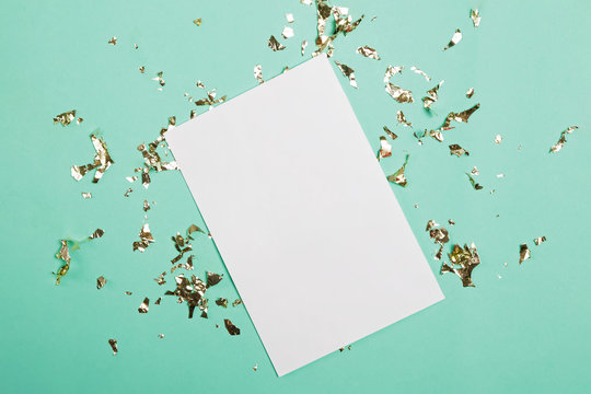 Blank paper with place for text on turquoise background with golden confetti