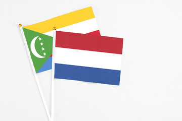 Netherlands and Comoros stick flags on white background. High quality fabric, miniature national flag. Peaceful global concept.White floor for copy space.