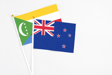 New Zealand and Comoros stick flags on white background. High quality fabric, miniature national flag. Peaceful global concept.White floor for copy space.