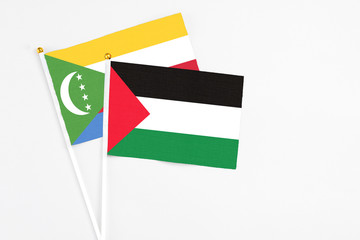 Palestine and Comoros stick flags on white background. High quality fabric, miniature national...
