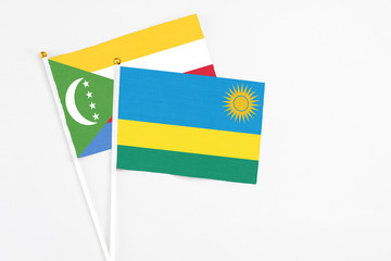 Rwanda and Comoros stick flags on white background. High quality fabric, miniature national flag. Peaceful global concept.White floor for copy space.