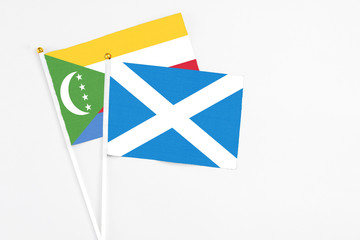 Scotland and Comoros stick flags on white background. High quality fabric, miniature national flag. Peaceful global concept.White floor for copy space.