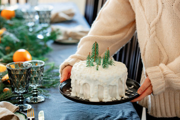 Woman holding christmas cake with cream over a table