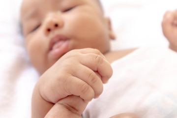 Newborn baby holding father's finger While sleeping comfortably on the white mattress During bedtime, the child's brain will work. To enhance Memory-boosting and learning-building skills