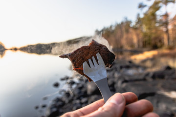 a smoking piece of bushcraft stone cooked meat on a titanium spork