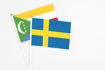 Sweden and Comoros stick flags on white background. High quality fabric, miniature national flag. Peaceful global concept.White floor for copy space.