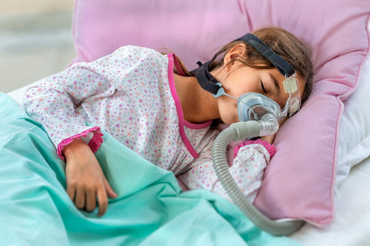 Child suffering from Sleep Apnea, wearing a respiratory mask.