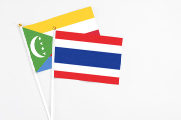 Thailand and Comoros stick flags on white background. High quality fabric, miniature national flag. Peaceful global concept.White floor for copy space.