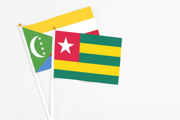 Togo and Comoros stick flags on white background. High quality fabric, miniature national flag. Peaceful global concept.White floor for copy space.