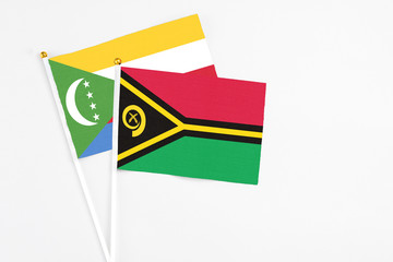 Vanuatu and Comoros stick flags on white background. High quality fabric, miniature national flag. Peaceful global concept.White floor for copy space.