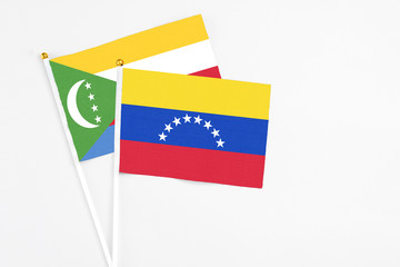Venezuela and Comoros stick flags on white background. High quality fabric, miniature national flag. Peaceful global concept.White floor for copy space.