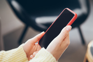 Woman in yellow jumper is holding in hands smart phone, close up image. Reading news, surfing the web / internet, chatting in social network in smartphone, tracking order, taxi