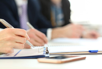 Business people in suits sitting at workplace making notes and solving problems