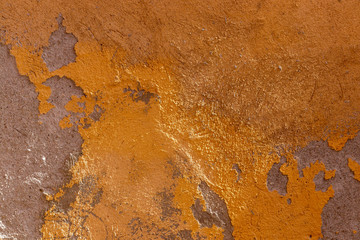 texture of old wall with paint peeling off cement.  Shades of ochre, burnt orange 