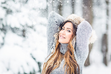 Young, beautiful woman with winter cap and gray sweater and closed eyes in winter landscape