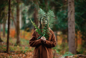 Style woman with fern branch in a autumn time forest
