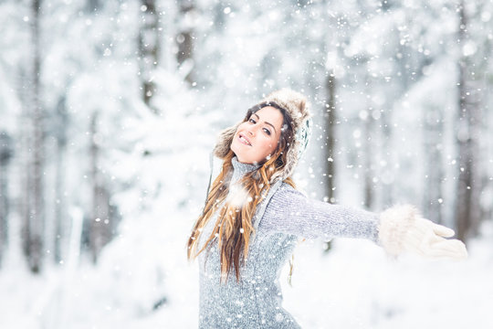 Young, beautiful,happy woman with winter cap and gray sweater and closed eyes in winter landscape