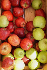 red and green apples in a wooden crate