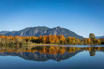 The calm, still waters of a large pond near Snoqualmie, Washington, reflect the beautiful fall...