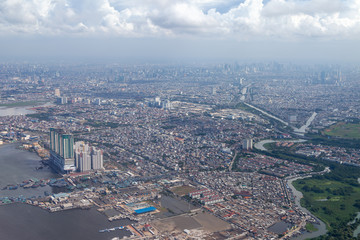 Aerial view of Jakarta. Sunda Kelapa Port can be seen in the lower left corner. Some clouds are visible on this day with high visibility. The central business district is also visible.