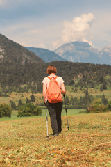 Fototapeta na wymiar Female hiker is trekking in alpine countryside landscape in autumn