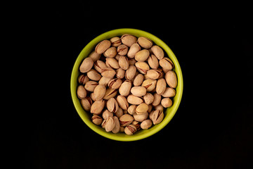 Pistachios in plates on a black background