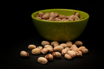 Scattered pistachios near the green plate