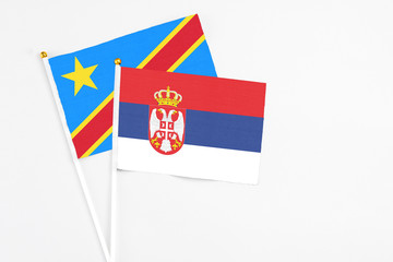 Serbia and Congo stick flags on white background. High quality fabric, miniature national flag. Peaceful global concept.White floor for copy space.