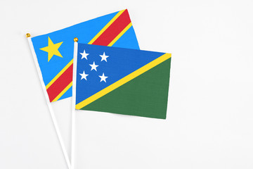 Solomon Islands and Congo stick flags on white background. High quality fabric, miniature national flag. Peaceful global concept.White floor for copy space.