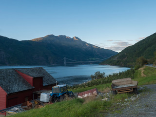 Fototapeta premium View on Hardanger Bridge across fjord Hardangerfjorden connects Ullensvang and Ulvikin, Norway. Longest tunnel to tunnel suspension bridge in the world 1380 meters. Summer day golden hour.