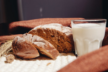 Loaf of brown bread and milk on table with sunshine on background