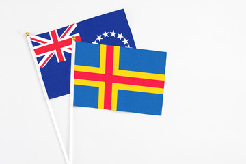 Aland Islands and Cook Islands stick flags on white background. High quality fabric, miniature national flag. Peaceful global concept.White floor for copy space.