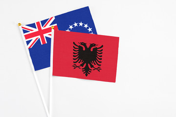 Albania and Cook Islands stick flags on white background. High quality fabric, miniature national flag. Peaceful global concept.White floor for copy space.