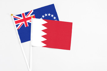 Fototapeta premium Bahrain and Cook Islands stick flags on white background. High quality fabric, miniature national flag. Peaceful global concept.White floor for copy space.