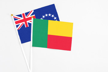Benin and Cook Islands stick flags on white background. High quality fabric, miniature national flag. Peaceful global concept.White floor for copy space.