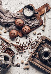 Coffee beans with coffee and muffins on grey textured background.