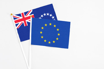 European Union and Cook Islands stick flags on white background. High quality fabric, miniature national flag. Peaceful global concept.White floor for copy space.