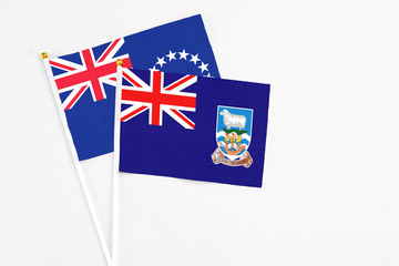 Fototapeta premium Falkland Islands and Cook Islands stick flags on white background. High quality fabric, miniature national flag. Peaceful global concept.White floor for copy space.