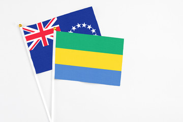 Gabon and Cook Islands stick flags on white background. High quality fabric, miniature national flag. Peaceful global concept.White floor for copy space.