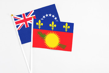 Guadeloupe and Cook Islands stick flags on white background. High quality fabric, miniature national flag. Peaceful global concept.White floor for copy space.