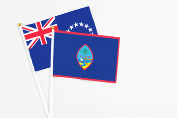Fototapeta premium Guam and Cook Islands stick flags on white background. High quality fabric, miniature national flag. Peaceful global concept.White floor for copy space.