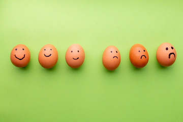 Smiling and sad eggs on a green background