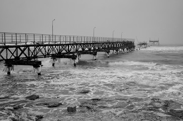 Powerful sea waves breaking on an old sea pier. Winter seascape.