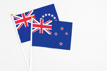 Fototapeta premium New Zealand and Cook Islands stick flags on white background. High quality fabric, miniature national flag. Peaceful global concept.White floor for copy space.