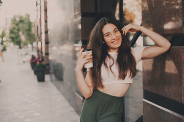 Fototapeta na wymiar Beautiful smiling woman drink coffee walking on the city in summer day.
