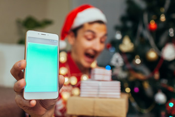 Christmas gifts delivery. Man ordered New year presents using smartphone. Happy guy holding gift boxes and phone