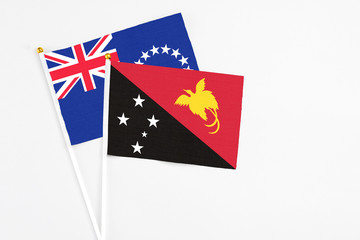 Papua New Guinea and Cook Islands stick flags on white background. High quality fabric, miniature national flag. Peaceful global concept.White floor for copy space.